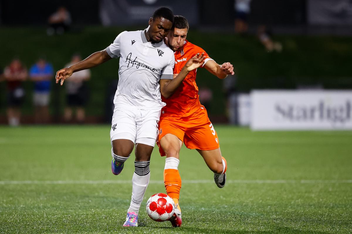 LANGLEY, CANADA - FRIDAY, AUGUST 22, 2025: Hugo Mbongue of Vancouver FC and Marko Jevremovic of Forge FC battle for the ball during the Canadian Premier League match between Vancouver FC and Forge FC on August 22, 2025 at Willoughby Community Park in Langley, British Columbia. (Photo by Gordon Kalisch/FastTrackSportsPhotography)